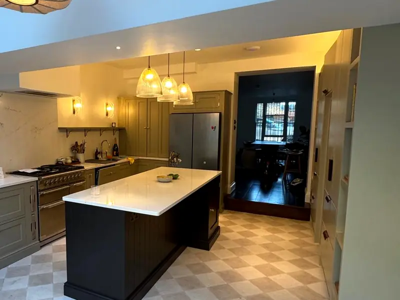 Finished kitchen with sage green cabinets, a dark island and a range cooker