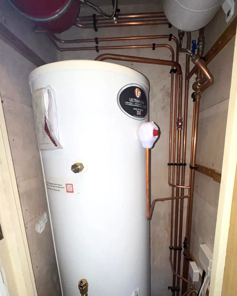 Hot water cylinder in an airing cupboard with neat copper pipework