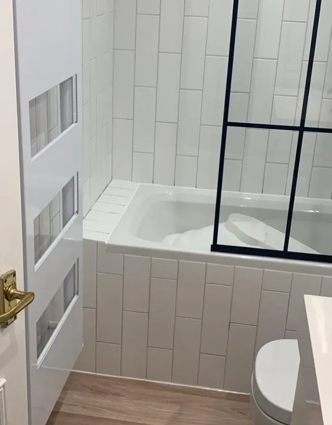 Bath with black framed screen and tiled bath panel